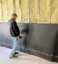 Mass-loaded vinyl is installed over a row-house party wall.