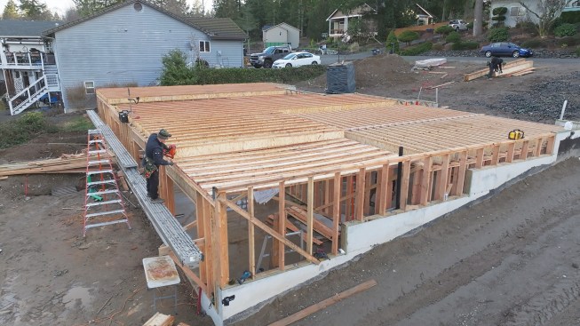 Here, a worker is installing one of the main-level I-joists above the walk-out portion of the basement at the back of the house.