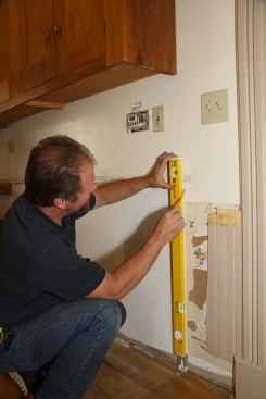 Carpenter Tim Donbeck starts by marking a plumb line on the wall where he’ll have a cabinet face frame or, in this case, an end panel.