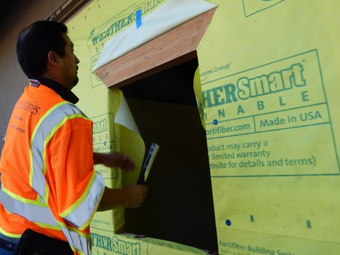 Step 1 (cont.). Cut Housewrap/WRB. Pull the resulting flaps into the RO. Secure flaps with a few staples, keeping the housewrap gently taut in the opening—do not over-pull the flaps. Cut a flap in the housewrap at the head at a 45° angle and to the width of the flashing, temporarily hold it up with tape.