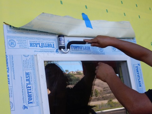 Step 8. Head Flashing. Install the head flashing last. Here, the installer flushed up the side and head flashing, but it’s preferable to extend each end past the side flashing. J-roll the peel-and-stick flat to fully adhere the membrane.