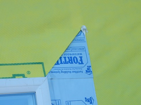 Step 9. Tape off head flap. Drop the head flap down. Prior to taping off, apply a dab of sealant at the top of the 45-degree cut. This may seem innocuous, but this little dab is important, particularly for drainable housewraps. Water can potentially get behind the tape at this juncture.