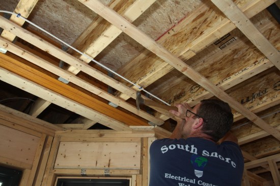 Strapped ceilings allow cable to run perpendicular to the joists if the cable is kept a minimum of 2 inches from the strapping. Otherwise the cable would be have to be fed through holes drilled in the joists.