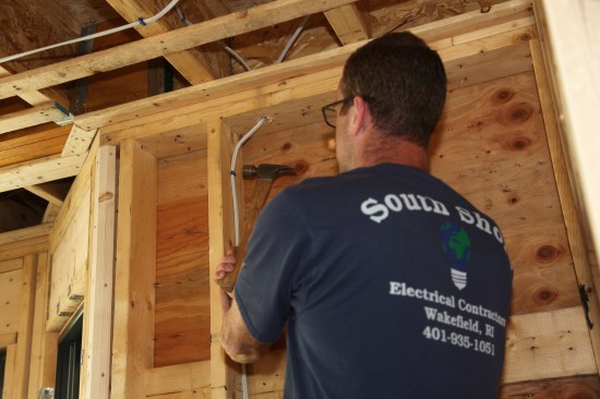 In a stud bay, the author drives the first staple about 6 inches down from the plate again keeping the cable relaxed in the transition from the drilled hole.