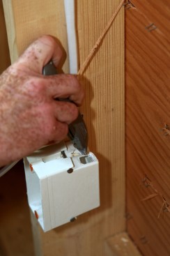 The author uses a the blunt end of a utility knife to remove the knock outs in the box for the two cables. 
