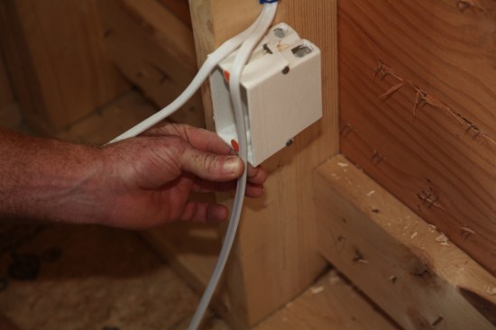 The author will loop the cables before they enter the box. To gauge where to begin stripping off the outer jacket he grips the cable at the bottom of the box with a finger and thumb. 