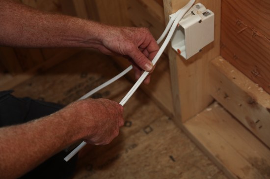 Starting just below his thumb the author carefully slits the outer jacket of the cable with a utility knife. For the second cable the author begins the slit about 1 inch farther down. 