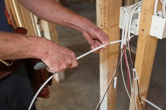 The author slits the outer jacket from the lower cable. Notice the progressively longer jacket length on the upper cables that have already been slit. The longer jacket lengths are needed to reach the farthest knockouts on the box.