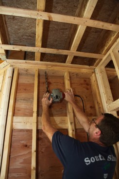 The author drills a 3/4-inch-diameter hole (big enough for a maximum of two cables) through the plates and into a joist bay.