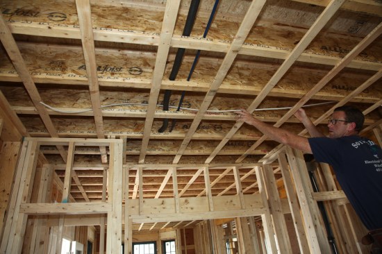 Taking care to keep the cable flat with no twists, the author feeds a length of cable through a joist bay. 