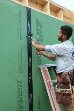 A roller applies the final "wetting" pressure that makes the adhesive on the surface of the tape flow into the topography of the sheathing surface.
