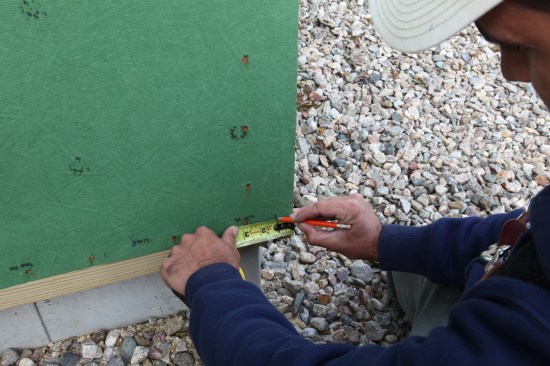 After wiping off the corner, the crew marks off 1 inch, the minimum required surface for flashing tape adhesion.