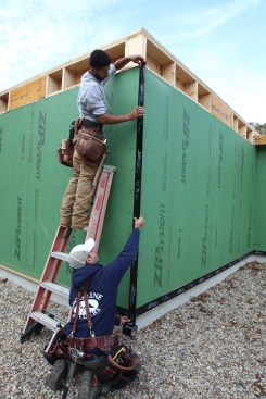 Working in tandem, one of the crew unrolls the flashing tape while the second crew member keeps the edge of the tape on the critical 1-inch line.