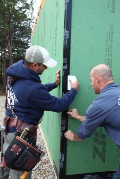 When wrapping an outside corner it is best to begin in the middle of the run of tape and work up and down. In this case the second crew member pulls the tape over to keep it going on perfectly straight and flat.