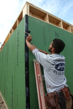After the tape has been adhered completely with no bubbles or fishmouths, a roller completes the adhering process on the adjacent wall of the corner. 