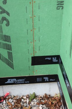 The sheathing was installed in pieces at this inside corner. The tape for that horizontal joint had to be applied before the vertical joints were taped. The tape for the horizontal joint extends through the corner far enough to be covered completely by the tape for the vertical joint.