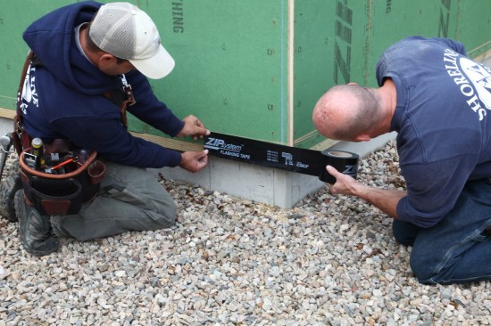 Two crew members start the course of tape a foot or so around the corner to ensure a good seal at the corner. 