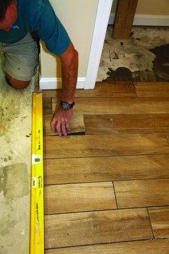 Then  install the tile using a  straightedge to keep  the edge of the tiles  in a perfectly straight line. Keep the edge  of the tile free of excess  mortar and grout.