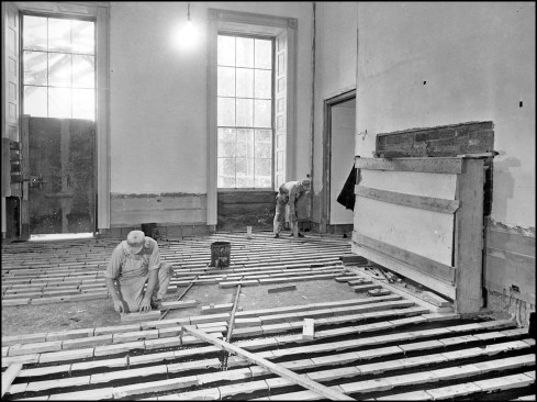 In preparation of laying strip subflooring in the first-floor Red Room, carpenters set wooden blocks in tar over the new concrete deck.