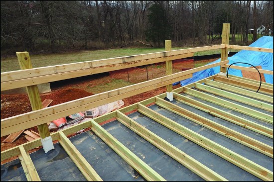 Though not usual, sleepers may be fastened to 2-bys laid on the flat, which helps distribute loads over a wider area, particularly when a protection board is not installed between the roof membrane and insulation or when a roof insulation with a lower compressive strength is used. Here, the guardrail posts are secured to the framing below and flashed with TPO post sleeve flashing, and the EPDM protection layer is fit around the posts.