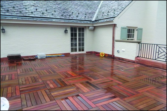 A newly-installed parquet-style wood “tile” deck installed over adjustable pedestal supports.