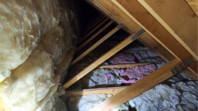 Here, in the unconditioned space behind the bonus-room knee walls, the bays of the vertical 2x4 web members of the attic trusses (which act as the knee wall) were infilled with 6-inch-thick kraft-faced R-21 batts, while the bays of the 2x10 bottom truss chords were infilled with 9-inch-thick kraft-faced R-30 batts. The fiberglass batt installations in the knee wall, ceiling, and connection “hall” area (not shown) were Grade II-level at best with large areas of Grade III work. (For information about insulation assembly grading, see Allison Bailes’ Energy Vanguard blog, “How to Grade the Installation Quality of Insulation” and JLC “Q&A: Installing Faced Batts.”)