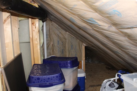 Kraft-faced fiberglass batts are installed in the rafter bays. Poly vapor barrier (shown here in the knee wall storage area above the covered entry) was installed in some locations, omitted or removed later in others. Much of the floor area of knee wall storage is above the outside. While there is insulation between the floor joists, there is no thermal break. Cold from conduction and infiltration makes it hard to keep this space warm.