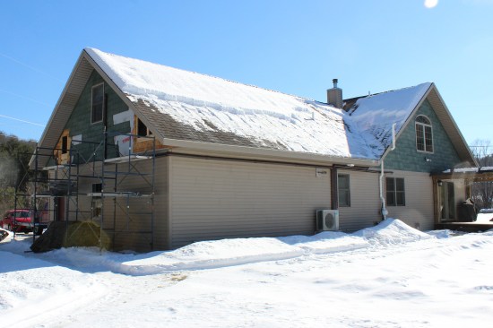 Holes were cut in the gable-end wall of the garage wing to access the spaces behind the bonus-room knee walls. (Note the raking of the roof’s perimeter of snow; the homeowner had to be diligent about snow raking to help prevent ice damming along the eaves and bottom of valleys.)