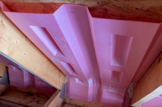 New insulation baffles installed in the unconditioned space behind the bonus-room knee wall. The somewhat fragile Propavents were taped at their articulated bends to help prevent them from breaking during installation (and over time). Loose-fill cellulose installed above the garage (see illustration, “Air-Sealing the Garage Wing”, on main page).