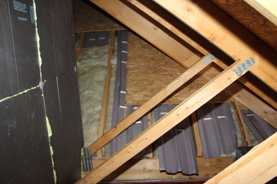 Note the existing ineffective thermal control where the garage wing intersects with the main roof. The main roof under the stick-framed section forming the valleys were left partially sheathed with large areas of exposed fiberglass and Propavent insulation baffles loosely placed.