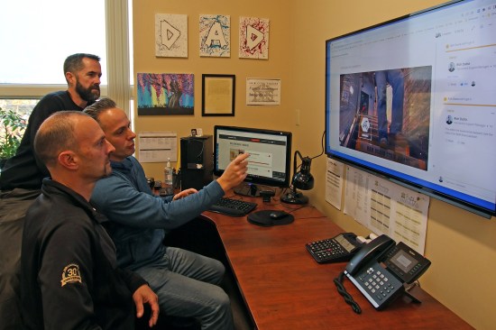 Operations support manager Rich Dutra (middle) and project lead managers Mike Whalen (background) and Rob Wheeler (foreground) review the results of an employee’s answers to a training video. The 360Learning LMS (learning management system) software has a summation sheet, which displays analytics and results data.