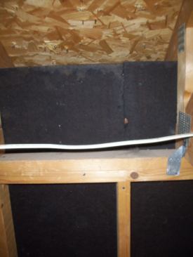 Not seeing anything unusual in the siding or in the roof, fascia, gutter, or soffit above the leaking wall, I went to take a look from inside the garage. Fortunately, there was no wall or ceiling covering, and the roof had been framed using raised-heel trusses. The exterior wall sheathing ran up the heel but stopped below the 2x4 truss tail. This space allowed me to see inside the soffit.