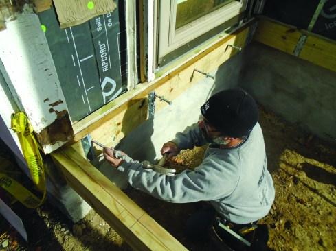 After predrilling through the ledger assembly, lags are tapped into the holes. They will anchor the tops of the ledger assemblies to the sills to supplement the hanging straps.