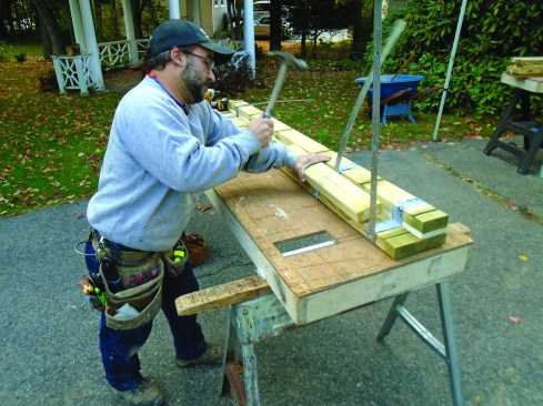 Author uses a wooden block to bend the strap into the inside corner formed by the spacer.