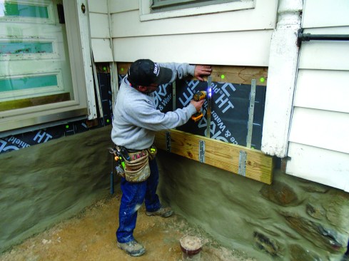 A screw in each strap holds the side-wall ledger in place. It will act as a guide for setting the rest of the deck perimeter.
