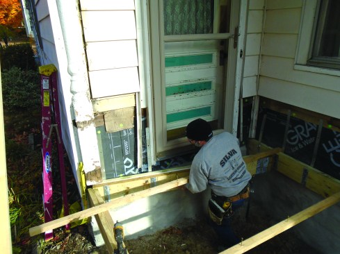 After setting the outside perimeter of the deck framing, author slides the final ledger into place.