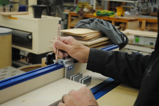 The stop system doubles as a measuring system for cutting on the miter-saw stand. To position the adhesive-backed measuring tape, slide the stop up to a board with a known length and mark the track.