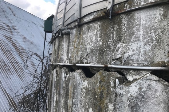 The concrete stave silo on this project was too far gone to save. A large, continuous crack along the top block course, gave the appearance that the top course and domed roof were well on their way to shearing off—the farm is located on an exposed lot prone to high winds, so the probability of this occurring was within reason. The clients agreed to demo the structure.