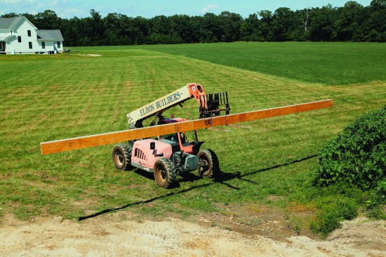The crew centered the ridge on the telehandler forks and held it in place with ratchet straps.