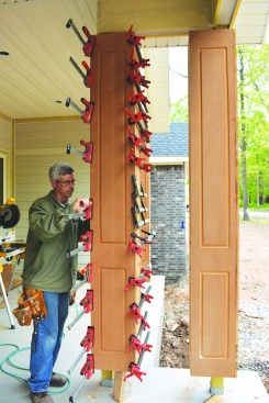 He tacked the halves together to align them, then nailed the second half of the column to the horizontal 2x4 blocks he had installed earlier. With the sides joined together with glue and nails, he clamped the assembly together.