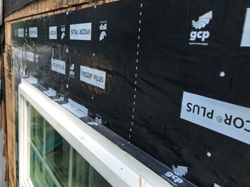 After renailing the window and running flashing tape along the sides, the author applied wide tape over the window lapping it over the top of the window and over the side flashing.