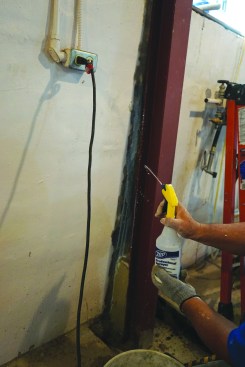 Before filling in the tapered gaps between the beams and the foundation wall, the crew sprayed liquid bonding agent on the bare concrete to help maximize adhesion.
