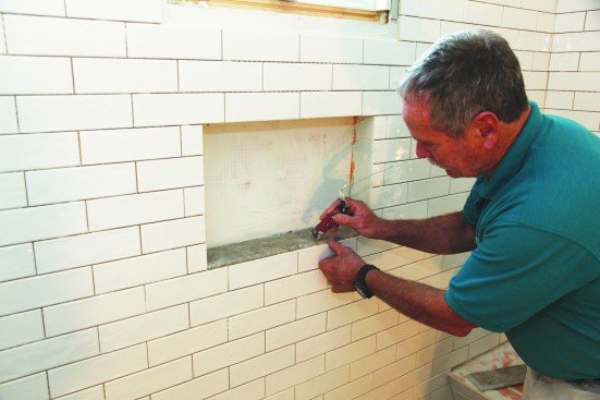 With the waterproofing complete, install the tile starting with the bottom of the niche, which should have a slight pitch for drainage.