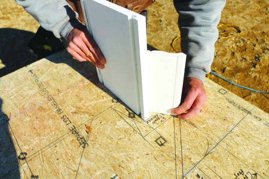 Visualizing the details of eaves is easier with a full-scale drawing. For this complex eaves with crown molding, the builder uses a section of the molding along with a piece of 1-by stock to ensure a proper layout.
