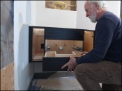 The author assembles a floating vanity after having aligned cabinet cut-outs with roughed-in plumbing.