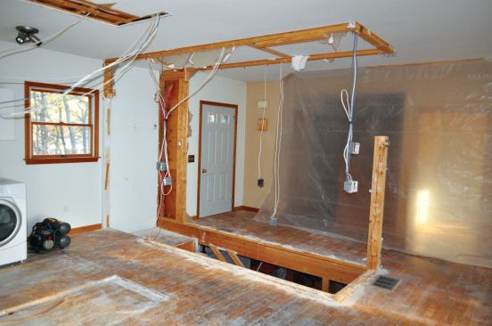 A truss roof directly above that section of the house meant that the interior partitions were non-structural, so first we removed the walls that separated the hallway and kitchen. Then we tore out the chaseway walls, exposing the stair hole while leaving the stairs—the only convenient access to the basement—in place.