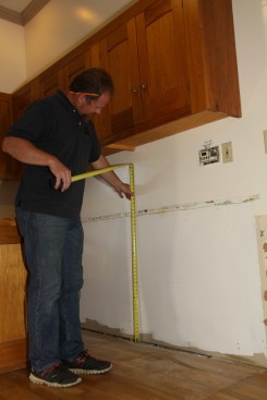 He checks the floor for high and low spots, as well as humps or dips along the cabinet run.