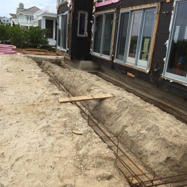 Rebar cages in both trenches are tied directly to the piles below to give the grade-beam footings their bearing strength.