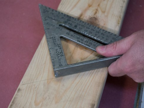 Seat cut. Set the flange of the square on the plumb line that marks the birdsmouth shoulder, and slide this flange to the approximate depth of your seat cut (following the 2/3 rule). In this case, the width of the carrying beam we are bearing on is 3 1/2 inches, and that’s close to what we end up with for the length of the seat cut.