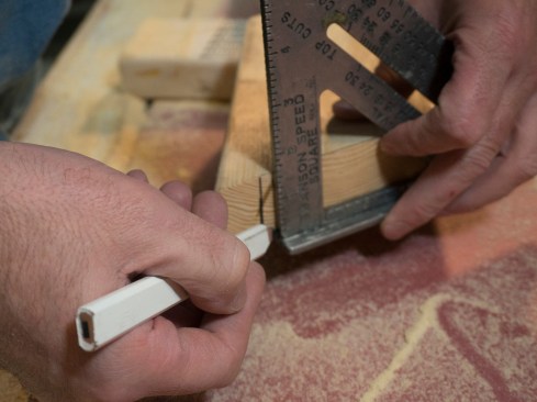 I also deduct another 1/4 to 1/2 inch to be sure that none of the tails will extend into the finished soffit. Holding a a square on the end of the rafter, I strike this mark.
